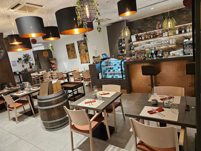 La salle, les tables dressées et le bar du restaurant
